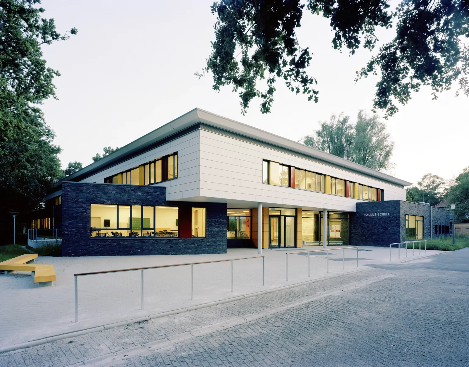 Moderne Schulgebäude der Paulus-Schule mit großen Fenstern und Bäumen im Hintergrund
